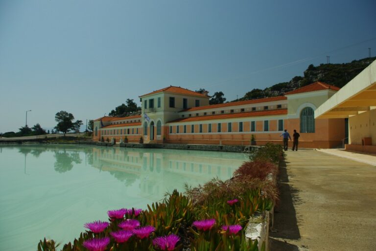 Methan, großes Gebäude, griechische Fahne, Blumen, am Wasser