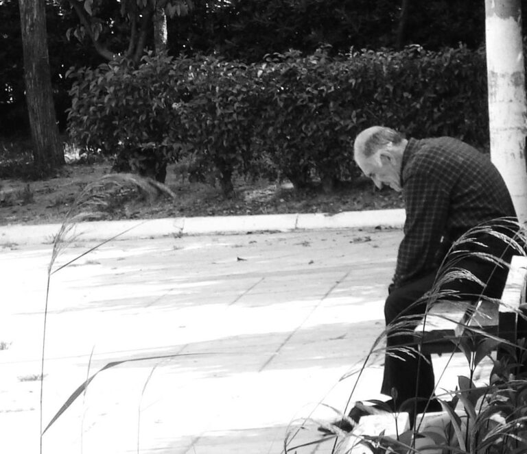 Foto sw: alter müder Mann sitzt auf Bank in Parkanlage